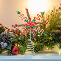 a christmas tree decorated with candy canes and decorations on top of a mantel