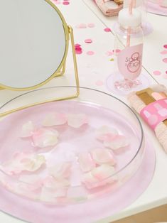 a table with pink plates and confetti on it, next to a mirror