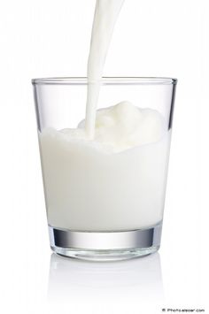 a glass filled with milk being poured into it