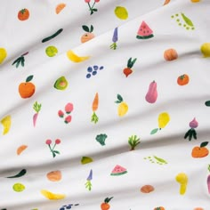 a white fabric with fruit and vegetables on it