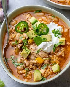 two bowls of chicken tortilla soup with sour cream and avocado on top