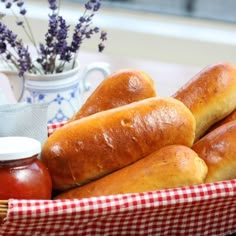 four loaves of bread sit in a basket next to a jar of honey and lavenders