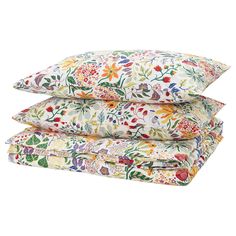 three pillows stacked on top of each other with colorful flowers and leaves printed on them