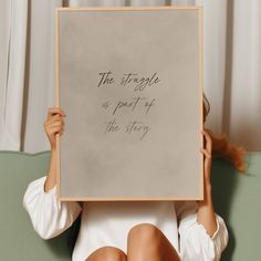 a woman holding up a sign that says the struggle is part of the story in front of her face