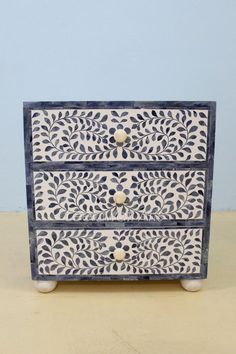 a white and blue painted dresser sitting on top of a table