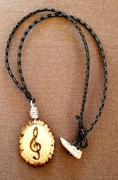 a wooden necklace with a musical note on it and a black cord around the neck