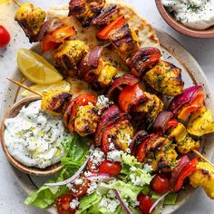 chicken kabobs on a plate with salad and pita bread