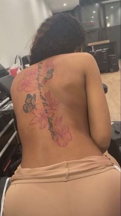 the back of a woman's body with flowers and butterflies on her lower back