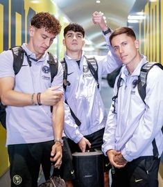 three young men standing next to each other in front of a yellow and black wall