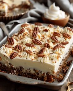 a piece of cake with pecans on top is sitting on a pan next to other desserts