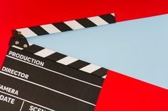 a black and white clapper on top of a red and blue background with the word production written below it