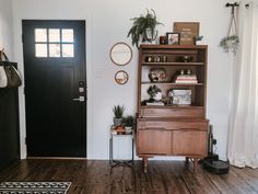 a living room filled with furniture and decor on top of hard wood flooring next to a black door