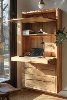 a laptop computer sitting on top of a wooden desk in front of a large window