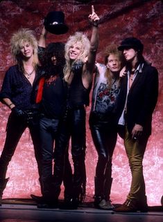 the group of rockers is posing for a photo in front of a red background