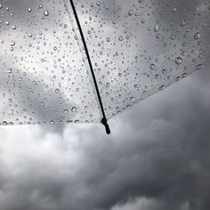 rain drops on the windshield of a car as it drives down a cloudy road in front of an overcast sky