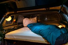 a bed in the back of a truck with pillows and blankets on it's sides