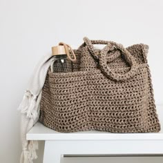 a crocheted bag sitting on top of a white table next to a bottle