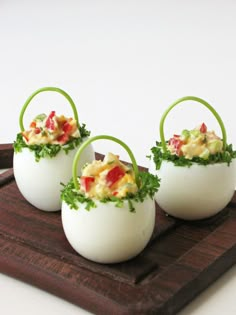 three deviled eggs with garnishes in them sitting on a cutting board