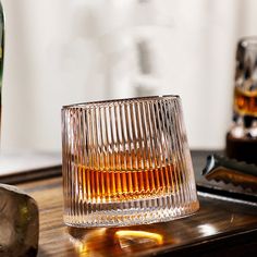 an empty glass sitting on top of a wooden table next to a bottle of alcohol