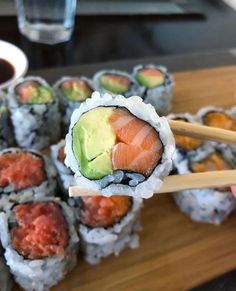 sushi rolls with avocado on top and chopsticks