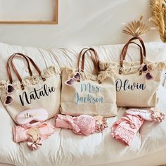 three personalized beach bags sitting on top of a white couch next to other items