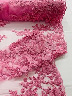 two pieces of pink lace with flowers on them, one is folded over the other