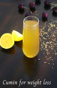 a glass filled with liquid sitting on top of a table next to sliced lemons