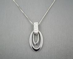 "14 KARAT WHITE GOLD MODERN PENDANT WITH HIGH POLISH . AVAILABLE SAME STYLE EARRINGS metal-14kwg weight-3.4gm FOR ADDITIONAL QUESTIONS ABOUT THIS PRODUCT: Please feel free to message us. We are quick to respond to all your inquiries. PLEASE choose as \"FAVORITE\" on the right so the item will be added to your favorites list and you may always revisit it. CUSTOM ORDERS: Please feel free to contact us if you could not find the piece you had in mind. We know how important it is to find the right je Modern White Gold Necklace With Diamond Accents, Oval White Gold Jewelry With Shiny Finish, Modern White Gold Oval Pendant Jewelry, Modern White Gold Diamond Necklace With Polished Finish, Modern White Gold Diamond Necklace With Round Pendant, Modern Oval Pendant Jewelry For Anniversary, Modern Sterling Silver Diamond Necklace In White Gold, Modern Silver Diamond-cut Necklace, Modern Silver Diamond Cut Necklace