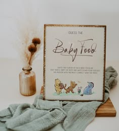 there is a baby food sign next to a glass bottle and some feathers on the table