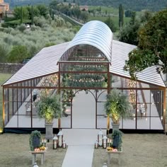 an outdoor wedding venue set up in the middle of a field with greenery and candles