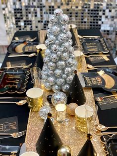 a table topped with lots of black and gold tablesettis covered in shiny silver balls