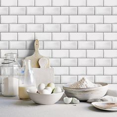 eggs, flour and other ingredients on a counter in front of a white brick wall