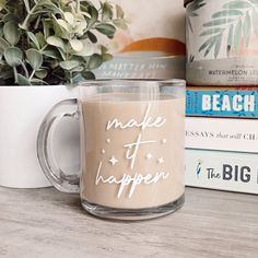 a coffee mug sitting on top of a table next to books and a potted plant