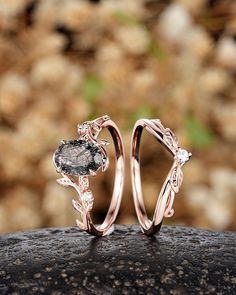 two wedding rings sitting on top of a rock in front of some leaves and flowers