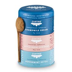 three tins of different flavors of tea with a wooden spoon in the top one