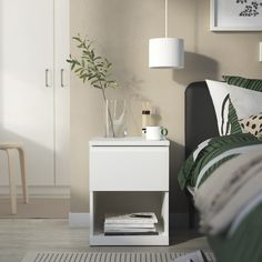 a white nightstand sitting next to a bed in a bedroom