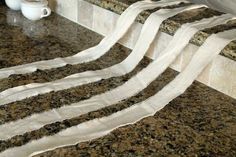 some white towels sitting on top of a counter next to a cup and coffee mug