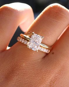 a woman's hand with a diamond ring on top of her finger and an engagement band