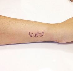 a person's arm with a small bird tattoo on the left side of it