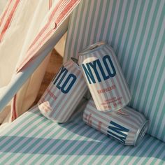 two cans of yogurt sitting on top of a striped chair next to an umbrella