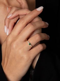 a woman's hands with white and green manicures holding onto her engagement ring