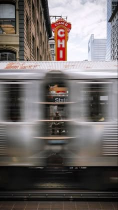 a blurry photo of a train passing by a building with a sign on it