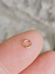 a person's finger with a tiny gold ring on it