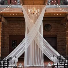 an indoor wedding venue with white draping and chandeliers