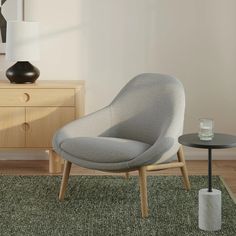 a grey chair sitting on top of a green rug next to a table and lamp