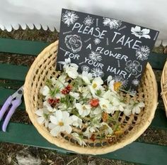 two baskets with flowers in them sitting on a bench next to a sign that says please take a flower for your hair