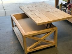 a wooden table sitting on top of a cement floor next to a shelf filled with tools