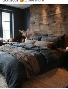 a large bed sitting next to a window with candles on top of it in front of a wooden headboard