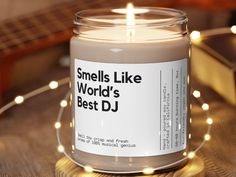 a candle that is sitting on a table with some lights around it and the words smells like world's best dj