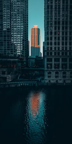 the city is lit up at night and reflecting in the water with skyscrapers on either side